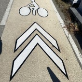 Symboles PREMARK contrastés homme à vélo et chevrons sur piste cyclable en Spraygrip RAL 1015